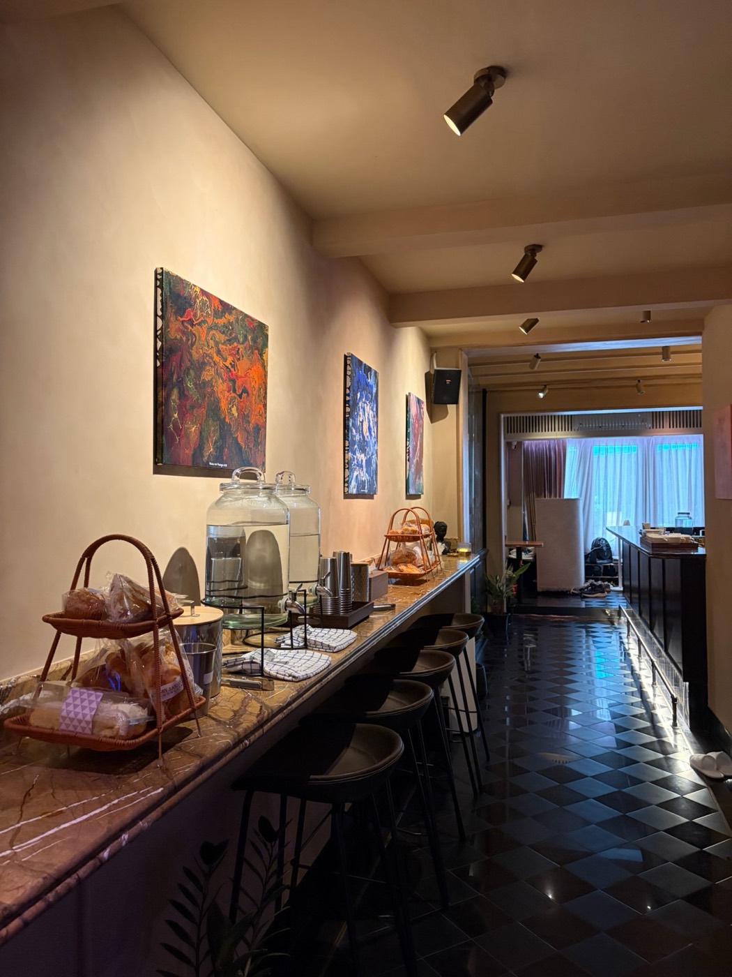 Paintings hanging in the gallery hall above a long marble counter